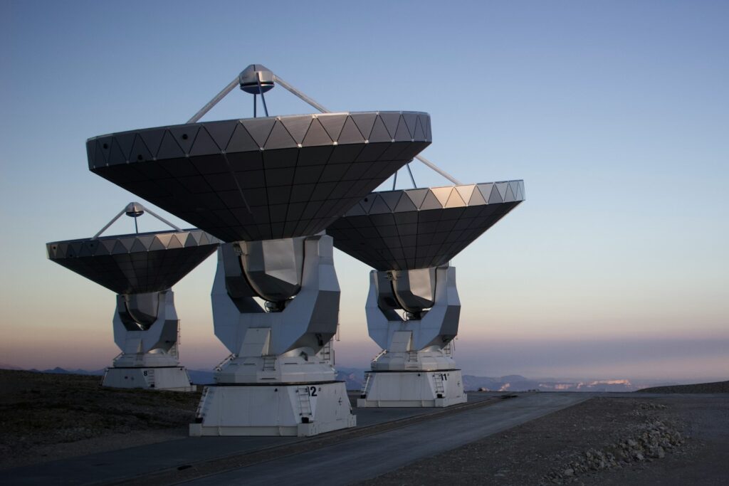 a large array of satellite dishes sitting on top of a dirt road